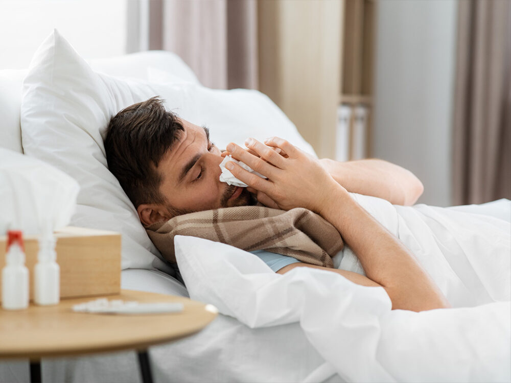 Man in bed suffering from flu symptoms